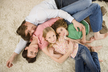 Family lying on floor in living room, elevated view - WESTF07339