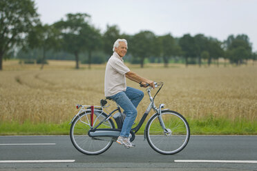 Senior man biking on road - WESTF07191