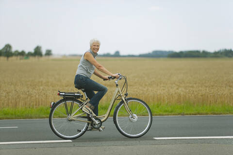 Senior woman biking on road stock photo