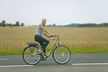 Senior woman biking on road - WESTF07190