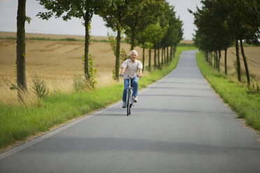 Senior man biking on road - WESTF07184