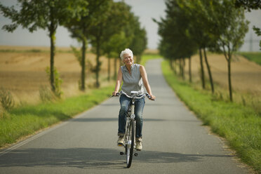 Senior woman biking on road - WESTF07181