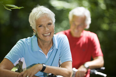 Älteres Paar mit Fahrrädern, Frau lächelnd, Porträt - WESTF07144