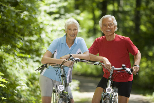 Senior couple with bikes, smiling, portrait - WESTF07142