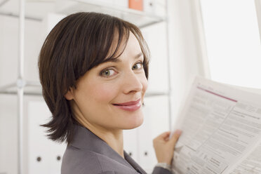 Businesswoman reading newspaper, portrait - WESTF07858