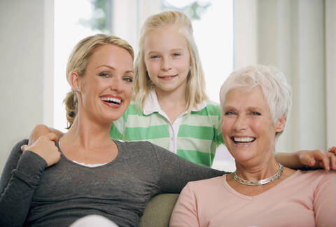 Mädchen (8-9) mit Mutter und Großmutter im Wohnzimmer, lächelnd, Porträt, lizenzfreies Stockfoto