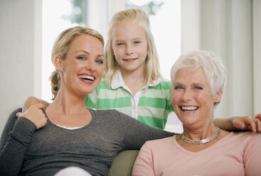 Mädchen (8-9) mit Mutter und Großmutter im Wohnzimmer, lächelnd, Porträt - HKF00202