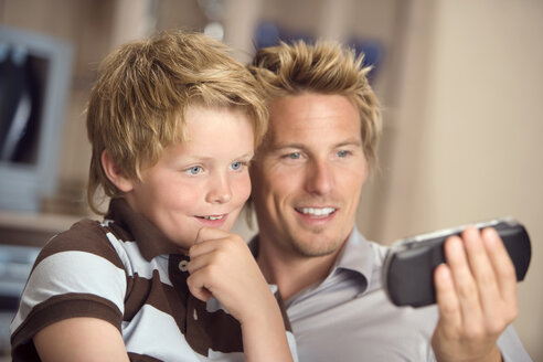 Father and son (10-11) looking at mobile phone together - HKF00188