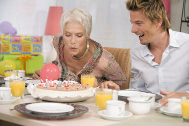 Woman blowing candle on torte, portrait - HKF00152