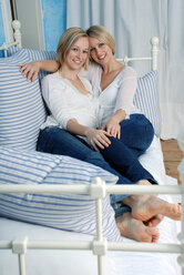 Zwei blonde Frauen entspannen sich auf einem Bett, Porträt - DKF00148
