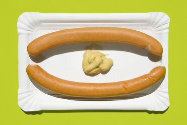 Two wieners with mustard on paper plate, elevated view - MUF00267