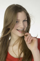 Brunette girl (13-14) eating chocolate bar - NHF00726