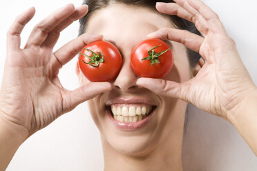 Brünette Frau bedeckt Augen mit Tomaten, Porträt - MAEF00949