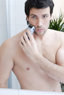 Young man man using electric razor, portrait - VRF00070