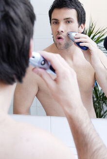 Young man man using electric razor, portrait - VRF00068