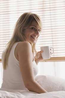 Blonde Frau hält eine Tasse Kaffee, lächelnd, Porträt - LDF00593