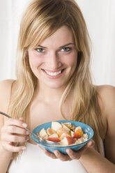 Young woman holding bowl of cereal, smiling, portrait - LDF00580