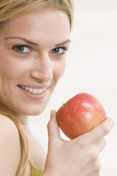 Blonde woman holding an apple, portrait - LDF00576