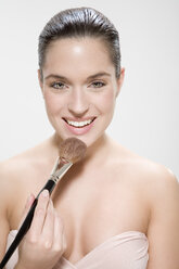 Young woman using make up brush, portrait - MAEF00964