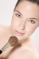 Young woman using make up brush, portrait - MAEF00961