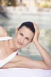 Young woman relaxing on pool side, portrait - ABF00223