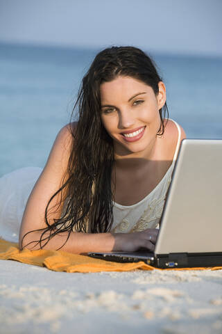 Asien, Thailand, Junge Frau mit Laptop am Strand, Porträt, lizenzfreies Stockfoto