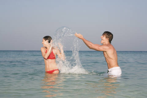 Asien, Thailand, Junges Pärchen im Meer, Wasser spritzen, lizenzfreies Stockfoto