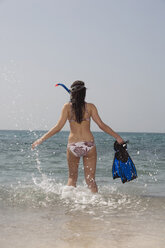 Asien, Thailand, Junge Frau mit Schnorchelausrüstung geht ins Wasser, Rückansicht - RDF00659