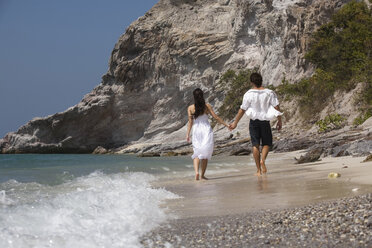 Asia, Thailand, Young couple walking hand in hand along beach, rear view - RDF00655