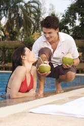 Asia, Thailand, Man handing cocktail to woman in pool - RDF00630