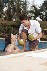 Asia, Thailand, Man handing cocktail to woman in pool - RDF00629