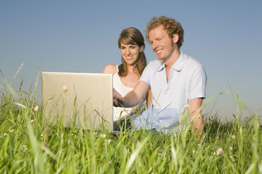 Germany, Bavaria, Young couple in meadow, using laptop, portrait - RDF00556