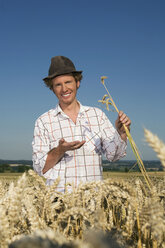 Germany, Bavaria, Farmer examining wheat growing in field - RDF00511