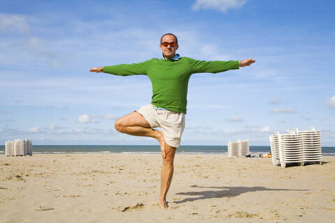 Belgien, Mann macht Yoga am Strand, lizenzfreies Stockfoto