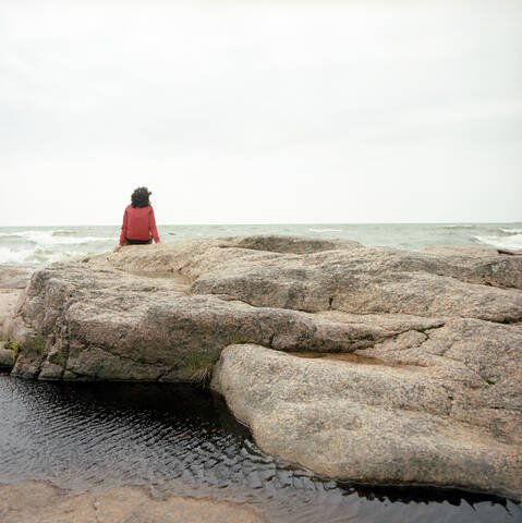 Finland, Woman sitting on the waterfront, rear view stock photo