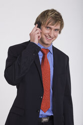 Junger Geschäftsmann, der ein Mobiltelefon benutzt, lächelnd - RDF00816