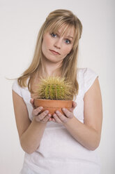 Junge Frau hält einen Kaktus in einem Blumentopf - RDF00811