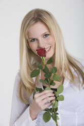 Junge Frau hält eine Rose, lächelnd, Porträt - RDF00802
