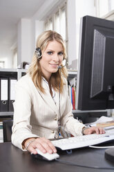 Junge Frau mit Headset, die einen Computer benutzt - RDF00796