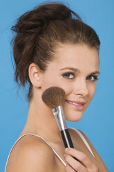 Young woman using makeup brush, portrait - RDF00741