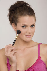 Young woman using a makeup brush - RDF00731