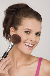 Young woman using a makeup brush - RDF00730