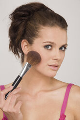 Young woman using a makeup brush - RDF00729