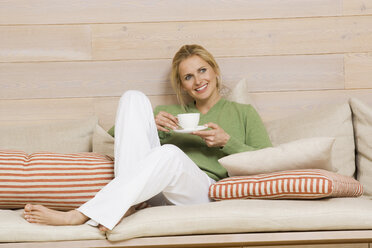 Young woman holding cup of coffee, smiling, portrait - WESTF07974