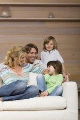 Family sitting on sofa, smiling, portrait - WESTF08118