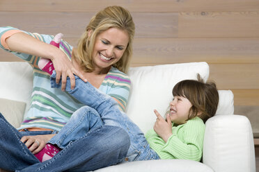 Mother and daughter (6-7) sitting on sofa, portrait - WESTF08115