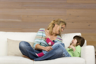 Mother and daughter (6-7) sitting on sofa, portrait - WESTF08114