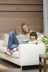 Mother and daughter (6-7) sitting on sofa, portrait - WESTF08113