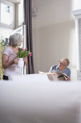 Ältere Frau hält Blumenvase, Mann liest Zeitung - WESTF08229