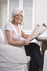 Senior woman holding newspaper, portrait - WESTF08208